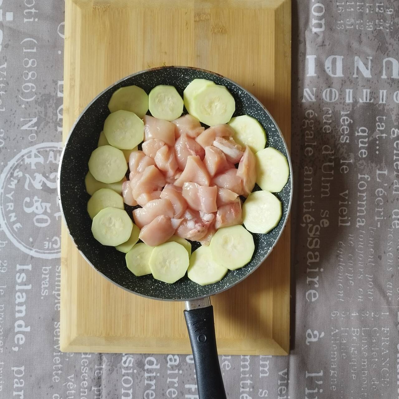 Chicken and zucchini in a frying pan on oil, reading to be cooked