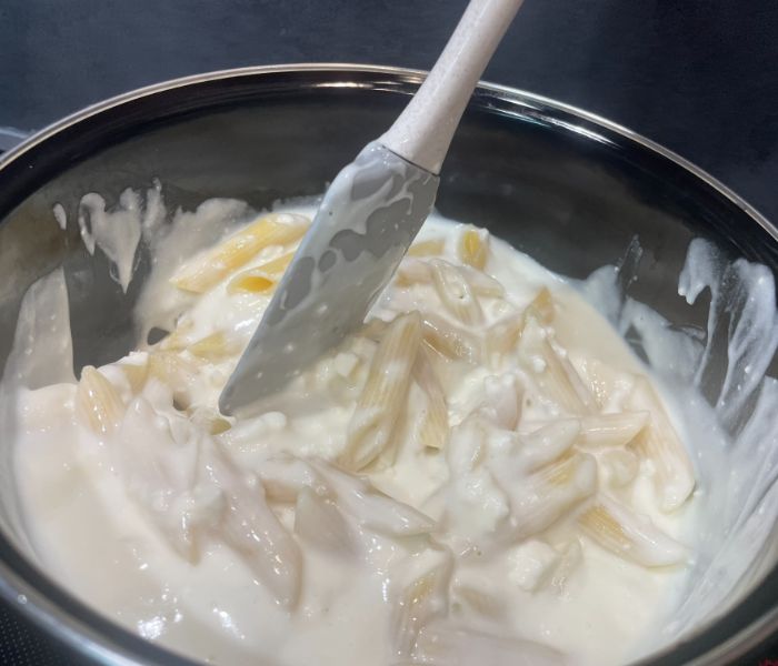 mixing pasta and cheese in a bowl