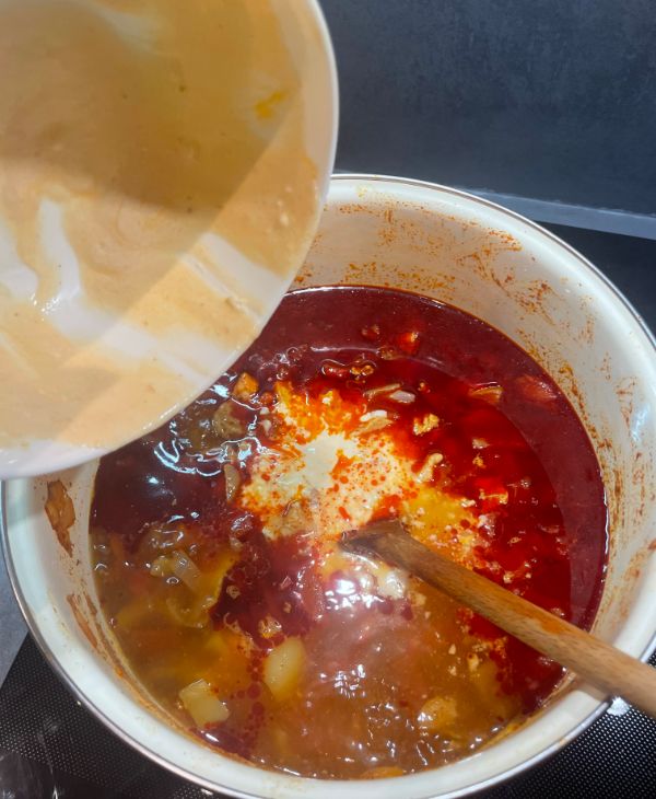 adding sour cream to chicken goulash while cooking