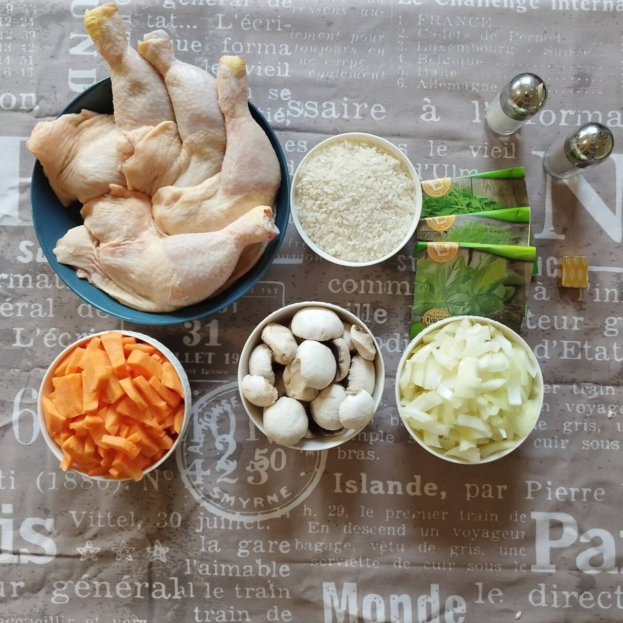 Ingredients for chicken rice pilaf: Chicken drumsticks, dill, basil, celery, rice, salt, pepper, mushrooms, onions, carrots shown on a the table.
