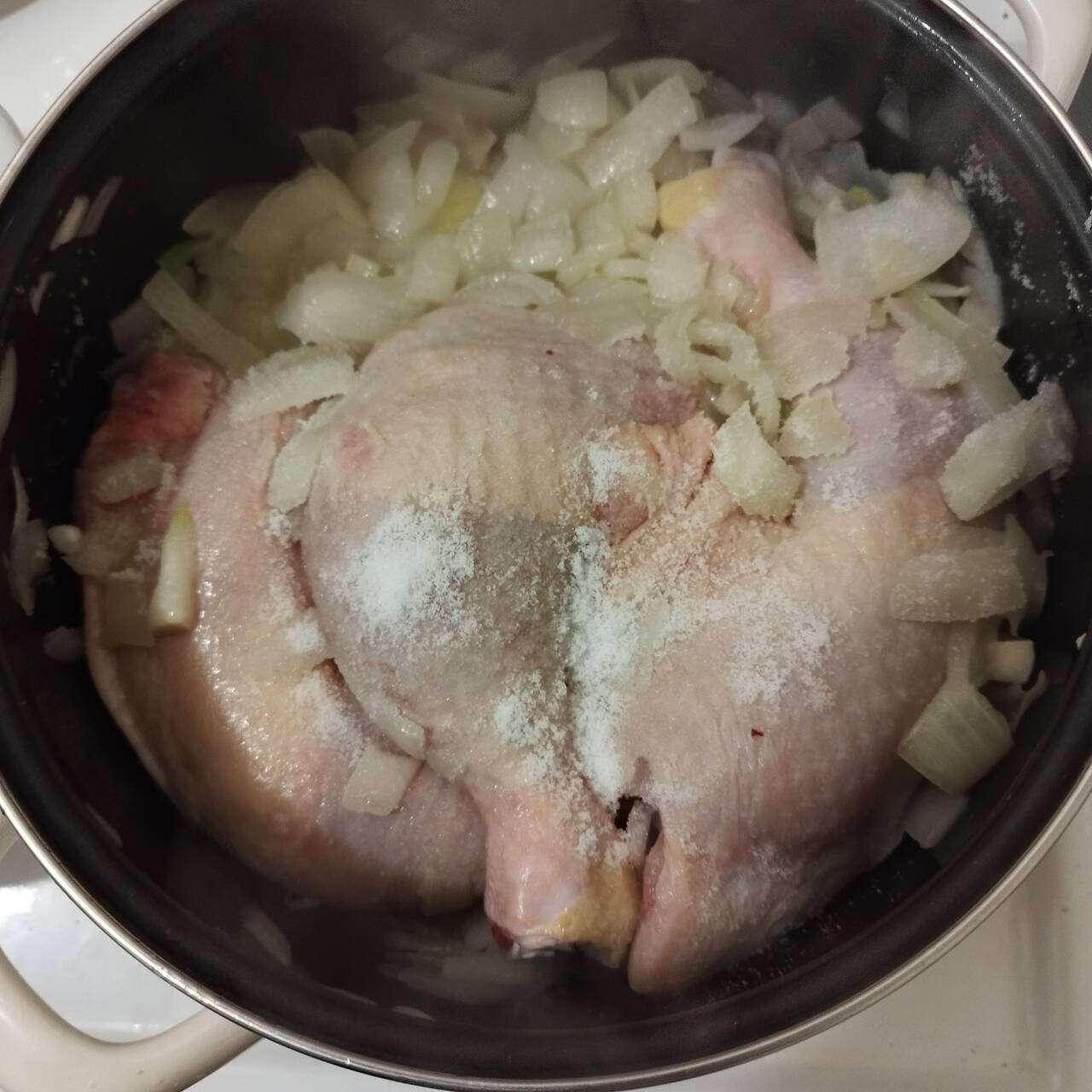 Onions and chicken drumsticks cooking in a pot