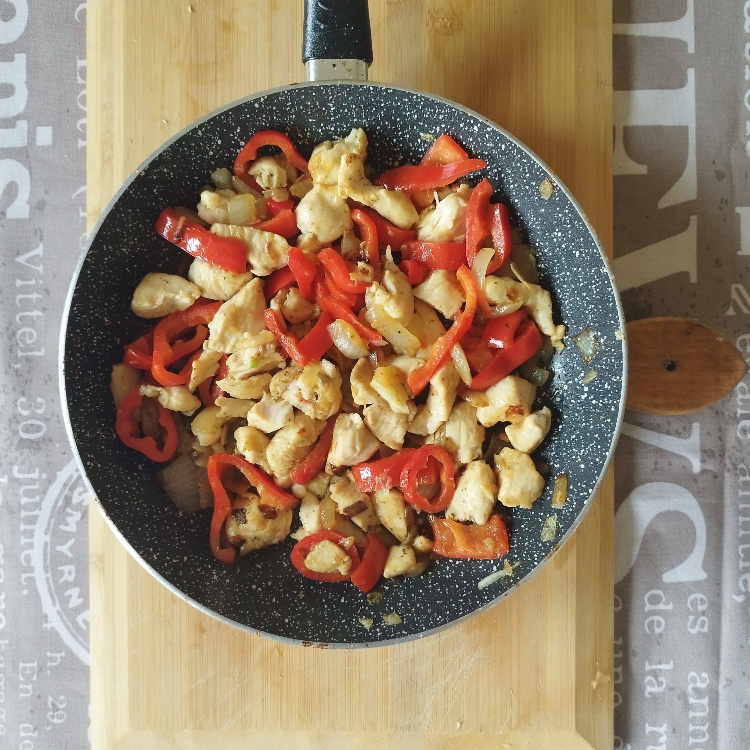 Chicken breasts, onions and bell peppers on a frying pan, done.