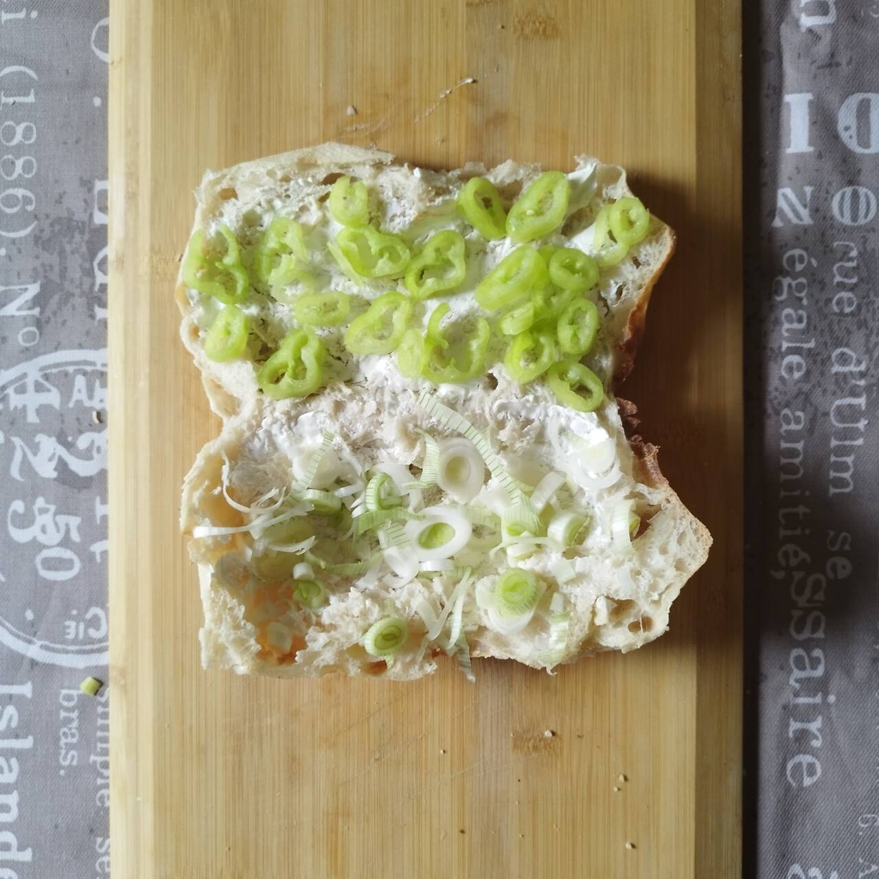 Spring onions, green bellpeppers and sour cream spread on flatbread cut through half